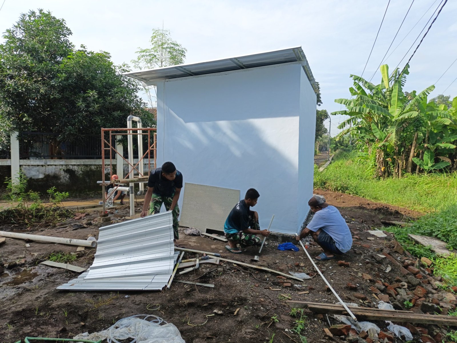 Prajurit Satgas TMMD 127 Kodim 0819/Pasuruan bersama warga Desa Wonosari sedang menyelesaikan pemasangan pipa saluran pada MCK komunal yang dibangun secara gotong royong.
