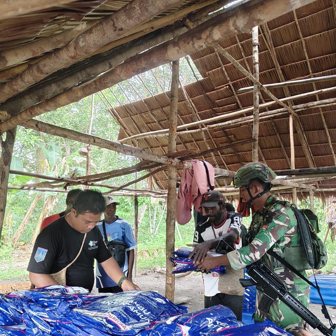 Personel Satgas Pamtas Yonif 123/Rajawali bersama petugas Puskesmas membagikan kelambu anti nyamuk kepada warga di perbatasan Papua. - thewasesanews.com