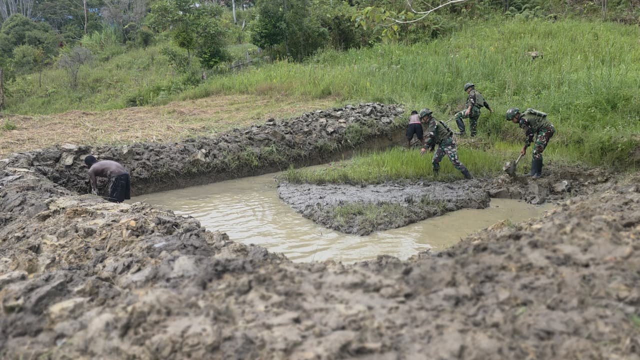 Prajurit Satgas Yonif 521/DY bersama warga Distrik Eragayam bergotong royong membangun kolam ikan budidaya sebagai sarana ketahanan pangan. - thewasesanews.com