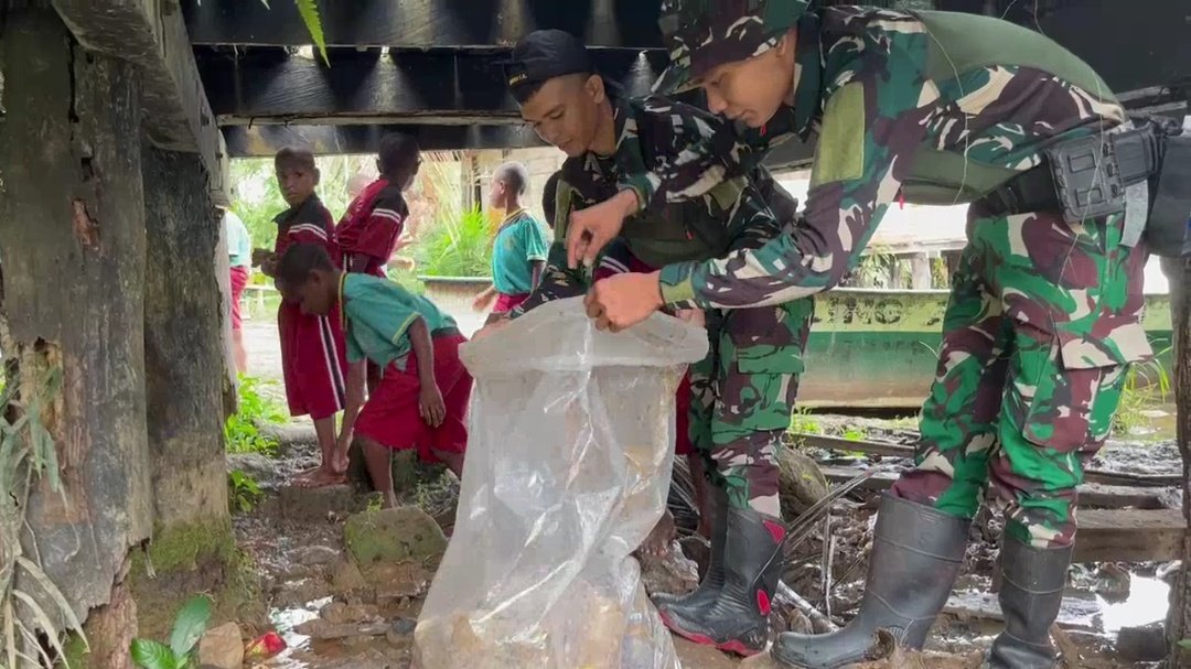 Personel Yonif 123 Rajawali bersama anak-anak SD dan warga Kampung Sahapikya sedang membersihkan area pelabuhan dari sampah plastik dan genangan air. - thewasesanews.com