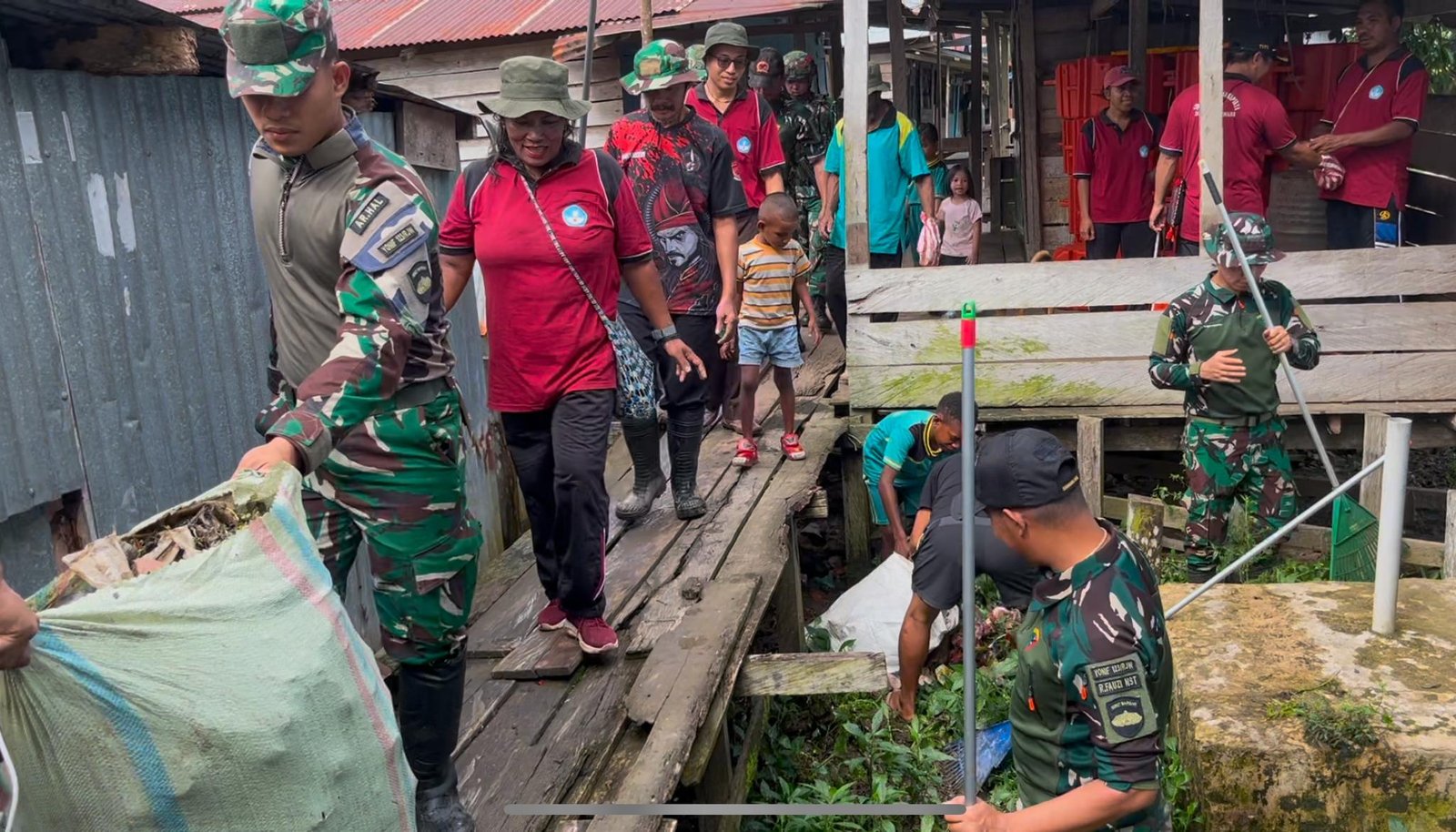 Personel Yonif 123 Rajawali bersama anak-anak SD dan warga Kampung Sahapikya sedang membersihkan area pelabuhan dari sampah plastik dan genangan air. - thewasesanews.com