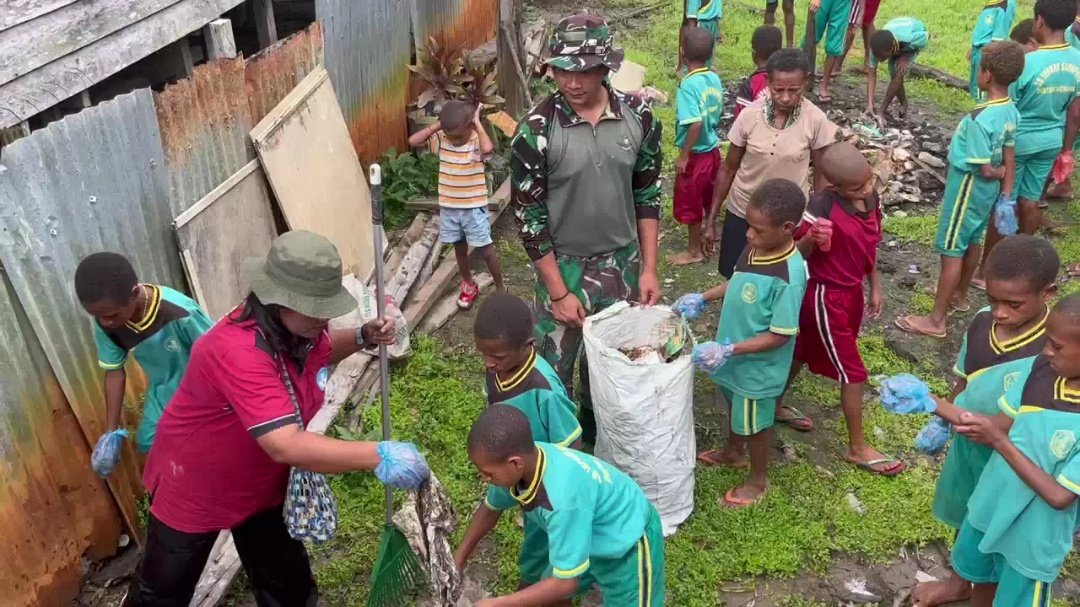 Personel Yonif 123 Rajawali bersama anak-anak SD dan warga Kampung Sahapikya sedang membersihkan area pelabuhan dari sampah plastik dan genangan air. - thewasesanews.com