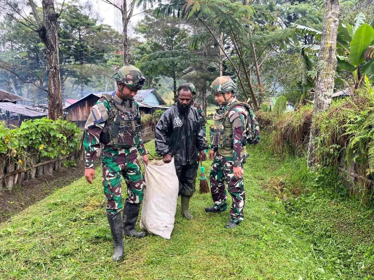 Prajurit Satgas Yonif 521/DY bersama anak-anak dan warga bergotong royong membersihkan rumput liar di jalan utama Kampung Bolakme Papua Pegunungan pada 10 April 2026. - thewasesanews.com