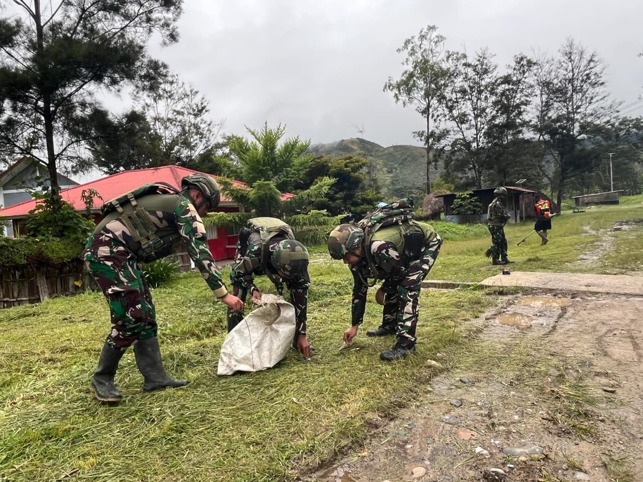 Prajurit Satgas Yonif 521/DY bersama anak-anak dan warga bergotong royong membersihkan rumput liar di jalan utama Kampung Bolakme Papua Pegunungan pada 10 April 2026. - thewasesanews.com