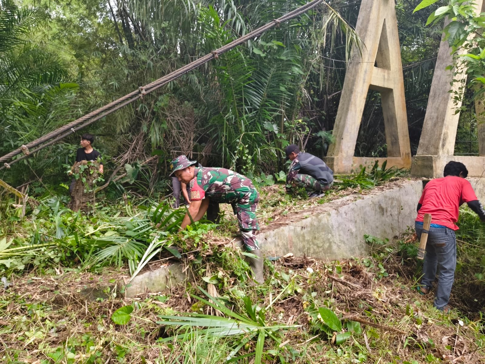 Personel Kodim 0212/TS bersama warga membangun jembatan gantung sepanjang 33 meter di Desa Parupuk Julu. - thewasesanews.com