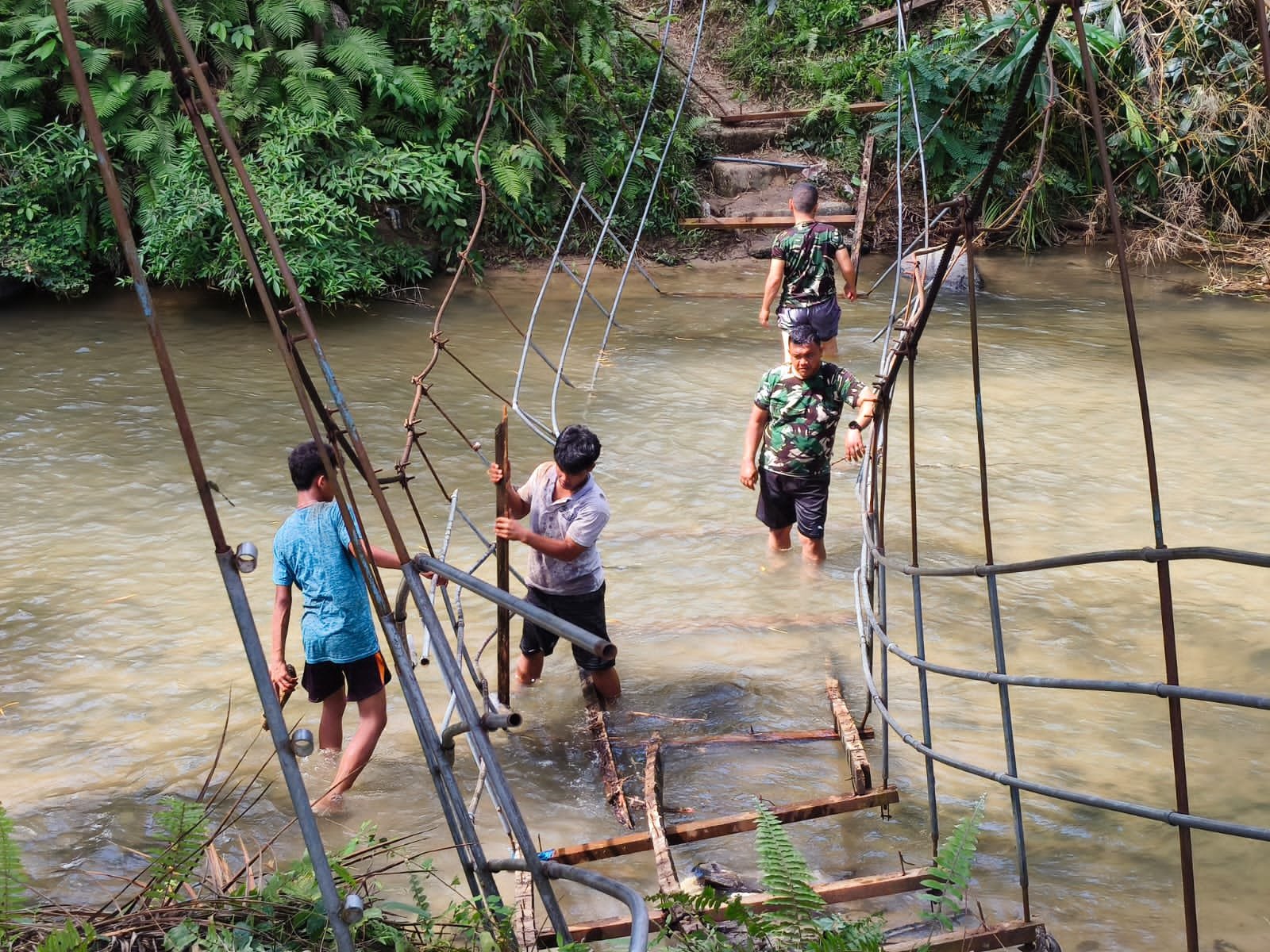 Personel Kodim 0212/TS bersama warga membangun jembatan gantung sepanjang 33 meter di Desa Parupuk Julu. - thewasesanews.com
