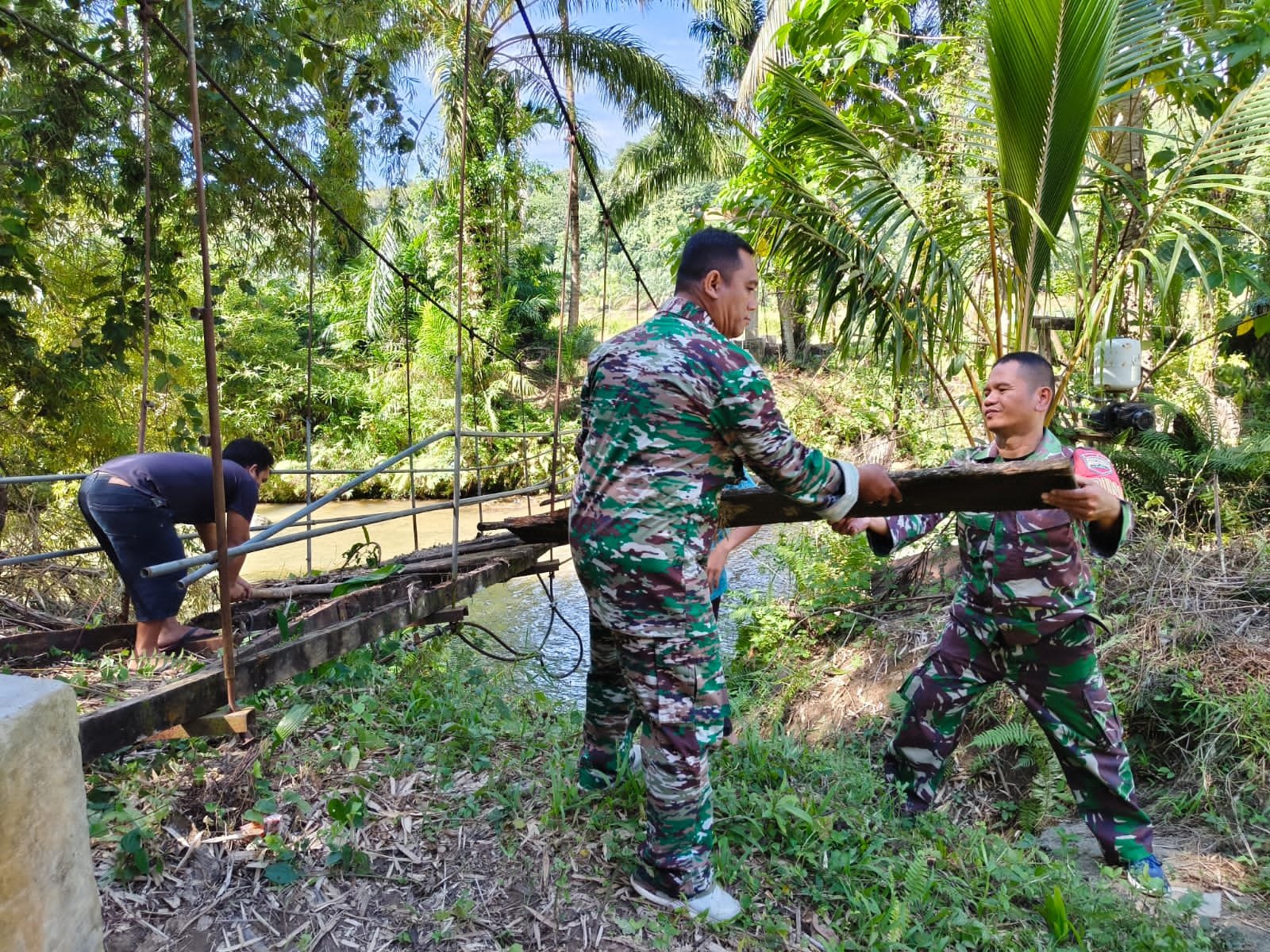 Personel Kodim 0212/TS bersama warga membangun jembatan gantung sepanjang 33 meter di Desa Parupuk Julu.- thewasesanews.com