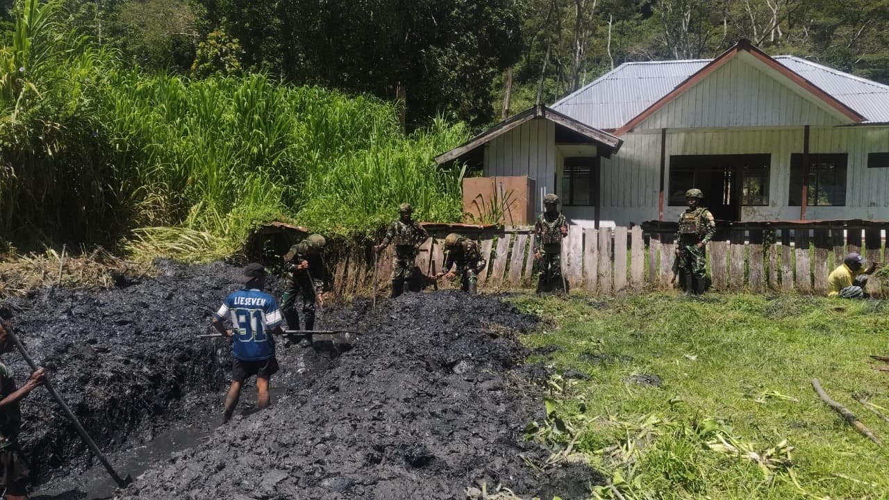 Personel Satgas Yonif 521/DY bersama warga Distrik Kurima Yahukimo saat melakukan aksi gotong royong membersihkan jalan dan selokan kampung. - thewasesanews.com