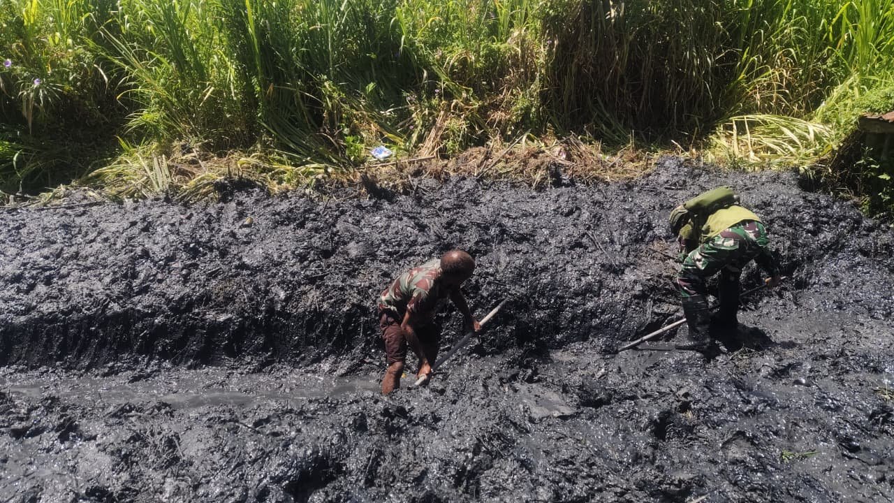 Personel Satgas Yonif 521/DY bersama warga Distrik Kurima Yahukimo saat melakukan aksi gotong royong membersihkan jalan dan selokan kampung. - thewasesanews.com