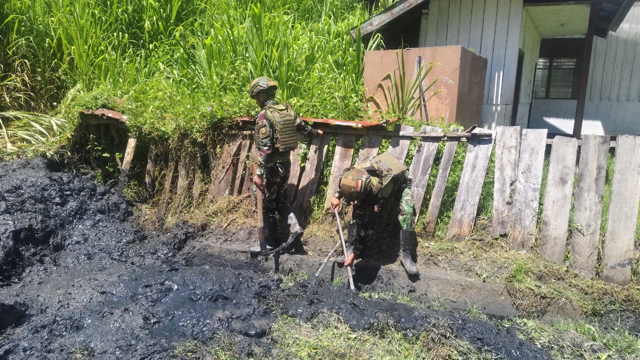 Personel Satgas Yonif 521/DY bersama warga Distrik Kurima Yahukimo saat melakukan aksi gotong royong membersihkan jalan dan selokan kampung. - thewasesanews.com