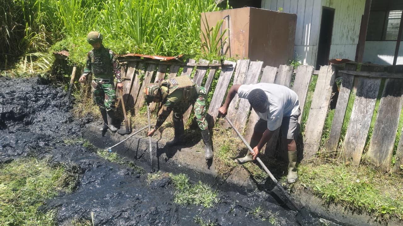 Personel Satgas Yonif 521/DY bersama warga Distrik Kurima Yahukimo saat melakukan aksi gotong royong membersihkan jalan dan selokan kampung. - thewasesanews.com
