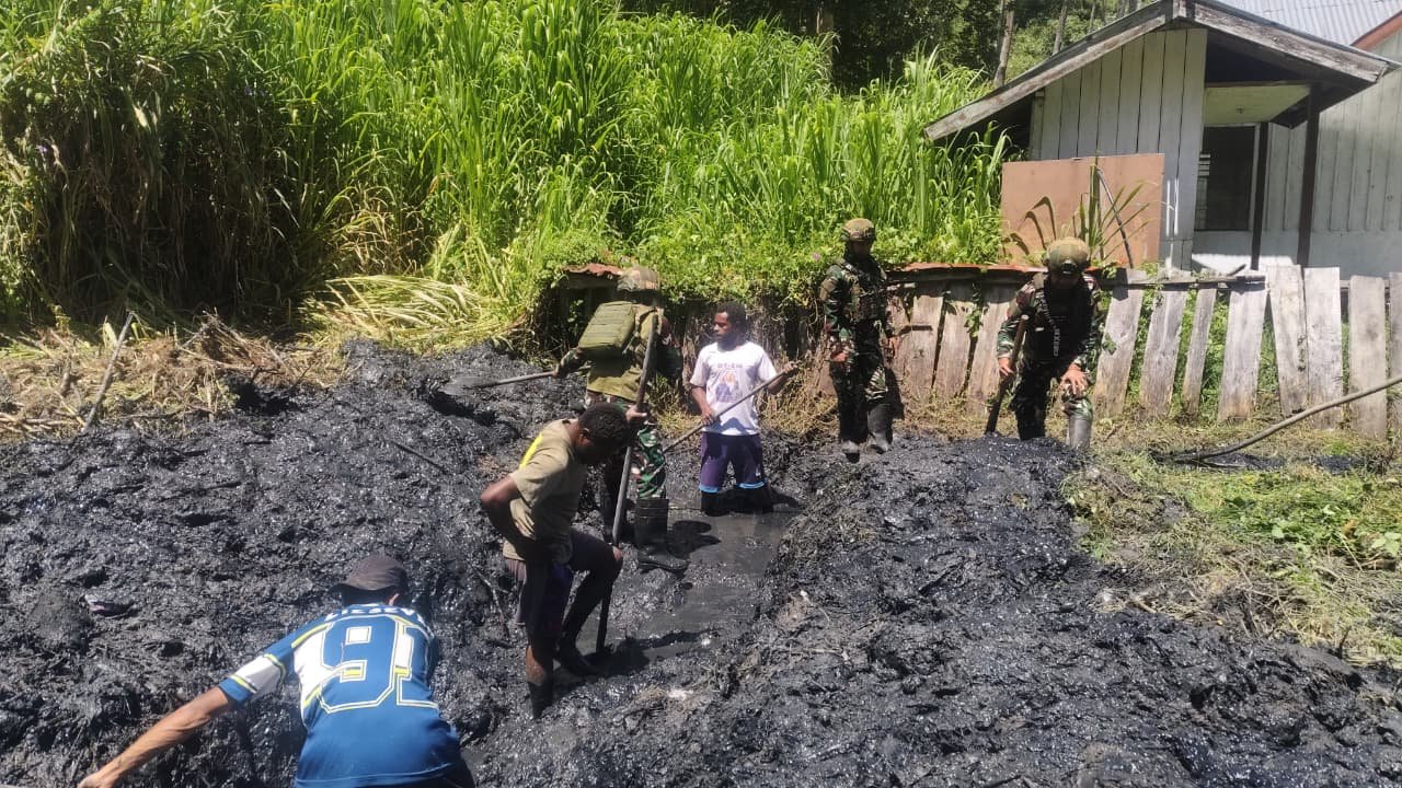 Personel Satgas Yonif 521/DY bersama warga Distrik Kurima Yahukimo saat melakukan aksi gotong royong membersihkan jalan dan selokan kampung. - thewasesanews.com