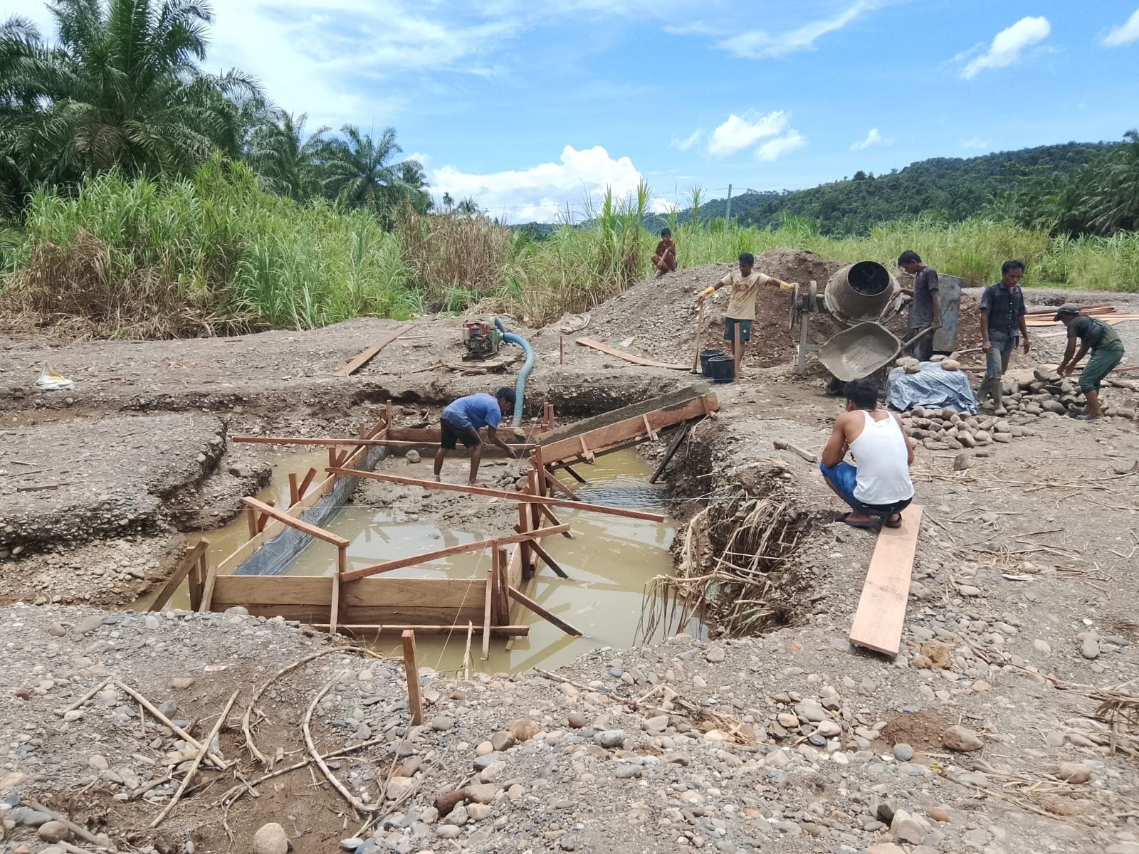 Personel Koramil 09/Sosa Kodim 0212/TS bersama warga Desa Parapat melakukan pengecoran pondasi jembatan gantung di Kecamatan Ulu Sosa. - thewasesanews.com