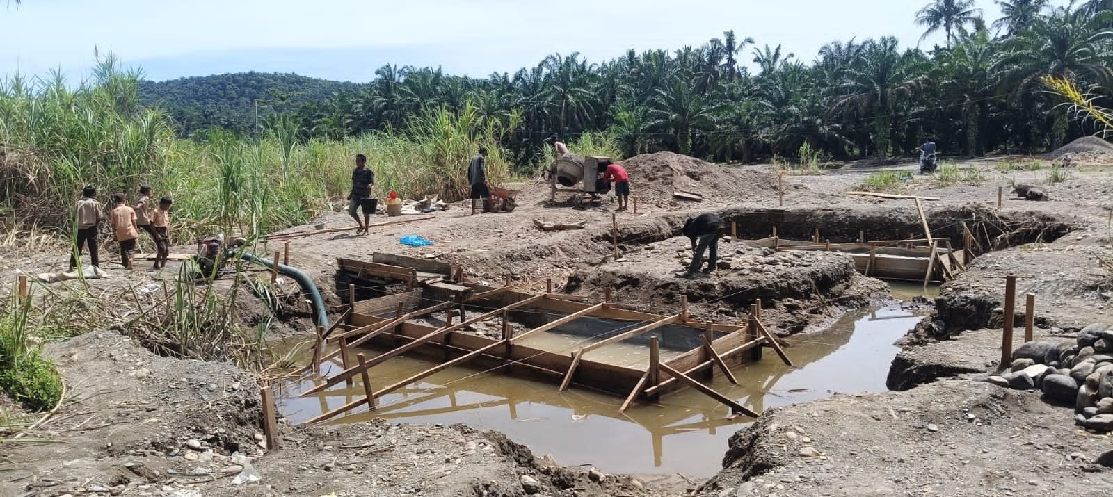 Personel Koramil 09/Sosa Kodim 0212/TS bersama warga Desa Parapat melakukan pengecoran pondasi jembatan gantung di Kecamatan Ulu Sosa. - thewasesanews.com