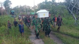 Personel Satgas Yonif 123/Rajawali membantu mengangkat jenazah warga Kampung Wonggi Papua saat prosesi pemakaman. - thewasesanews.com