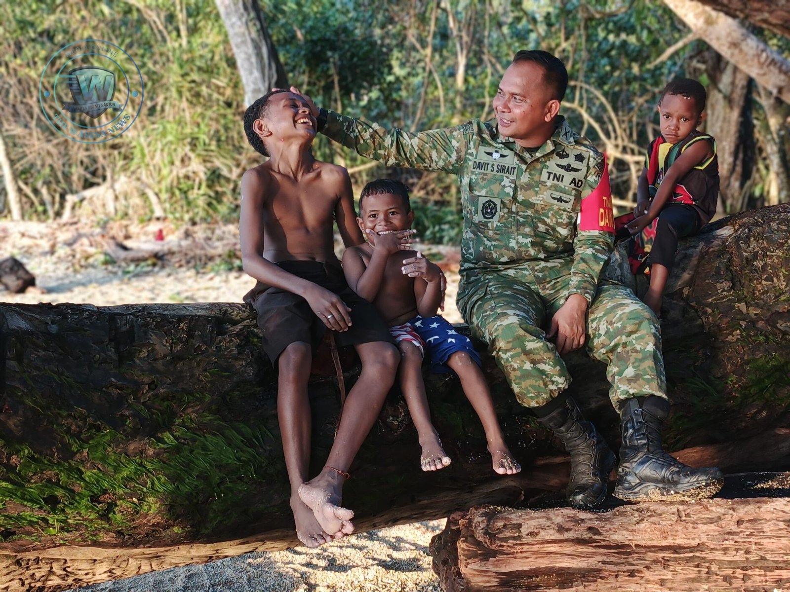Dandim 1801/Manokwari Letkol Inf Davit Sutrisno Sirait saat duduk bersama anak-anak Kampung Tanah Rubuh di tepi pantai dalam pelaksanaan TMMD Ke-128. - thewasesanews.com